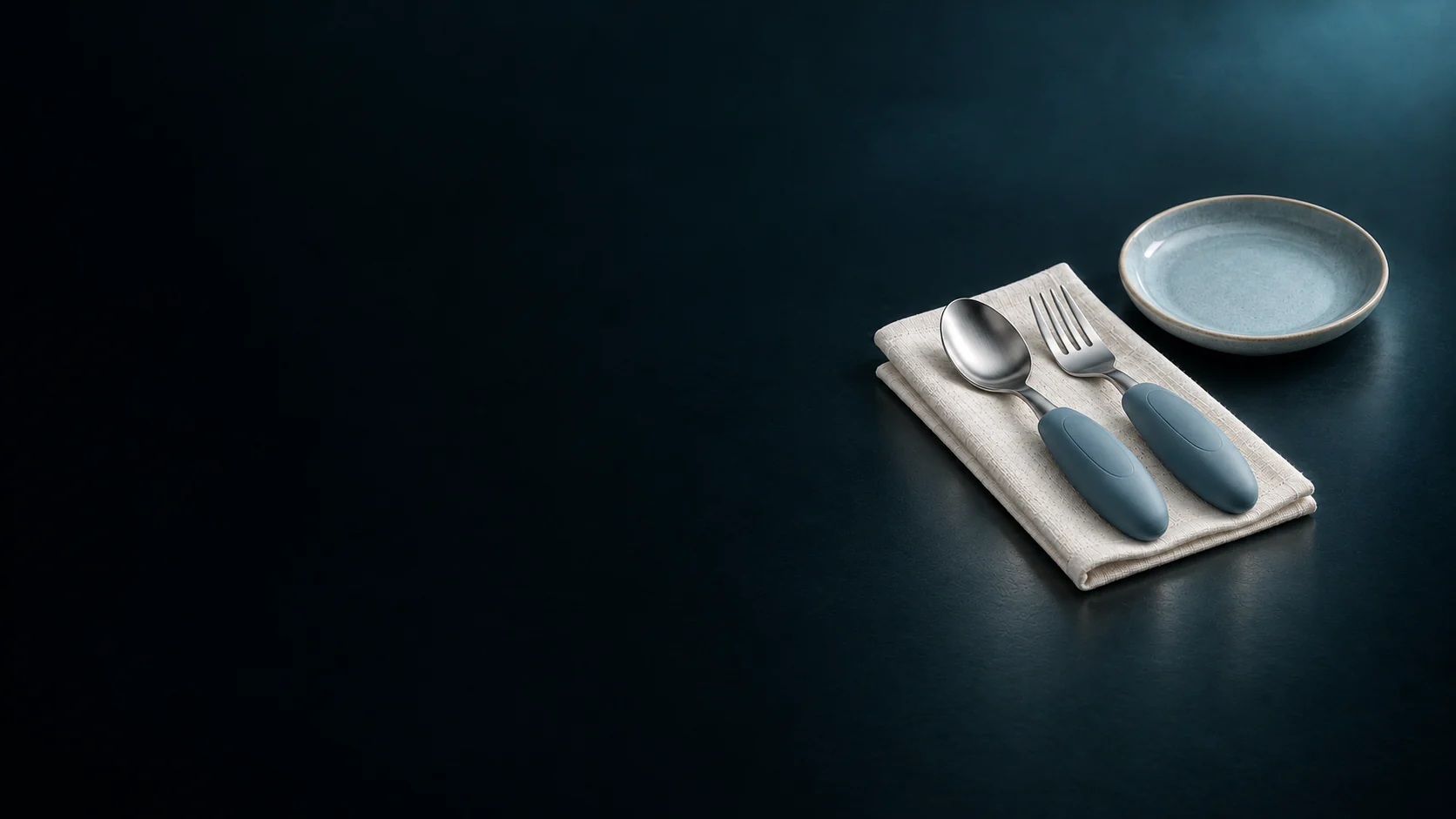 Spoon and fork with thick oval blue handles beside an empty plate.