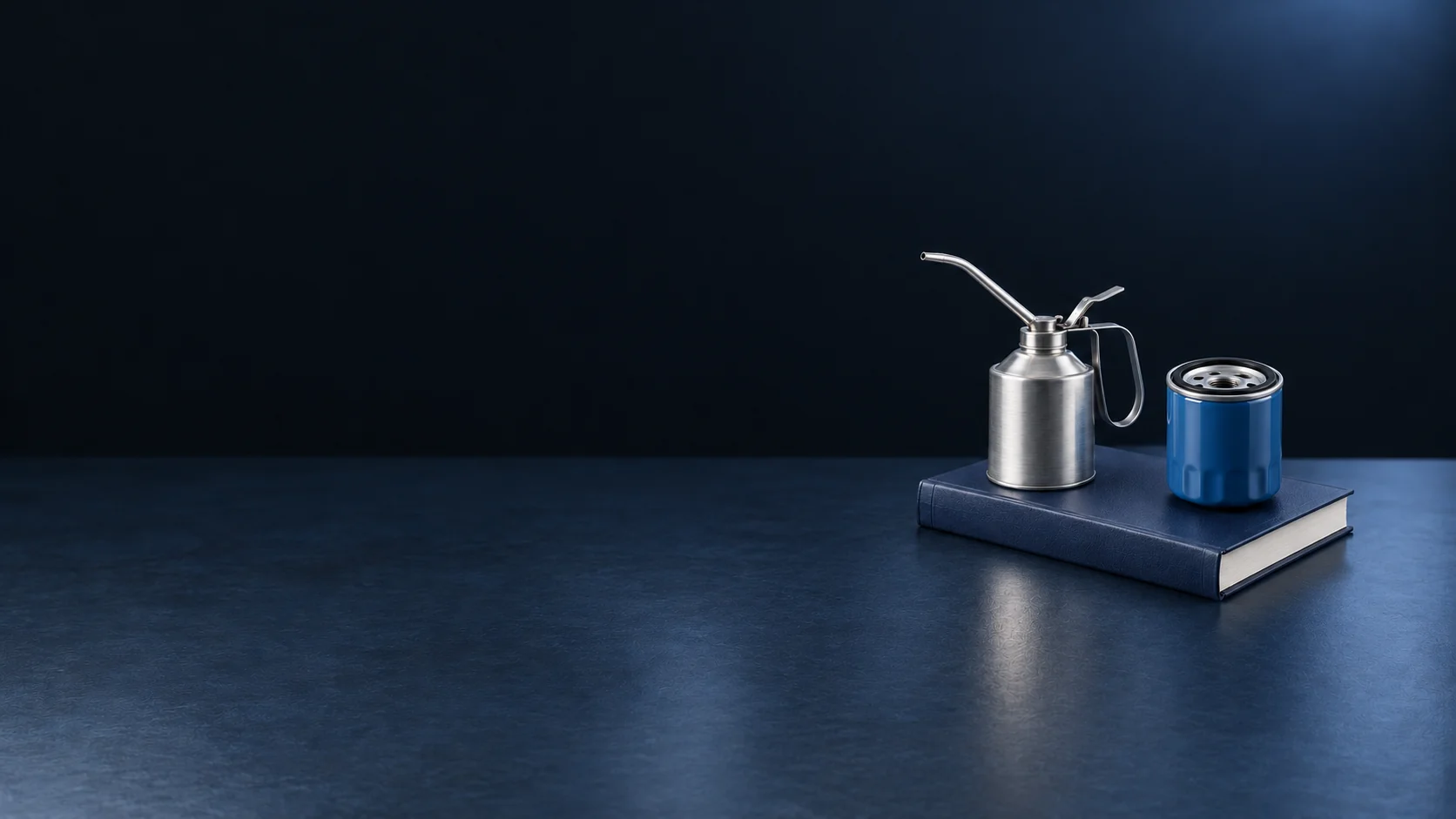 A brushed-metal oil can and blue filter on a closed navy service manual.