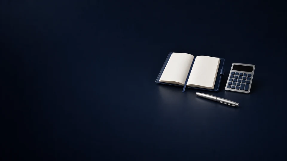 An open blank navy ledger beside an unmarked calculator and a capped silver pen.
