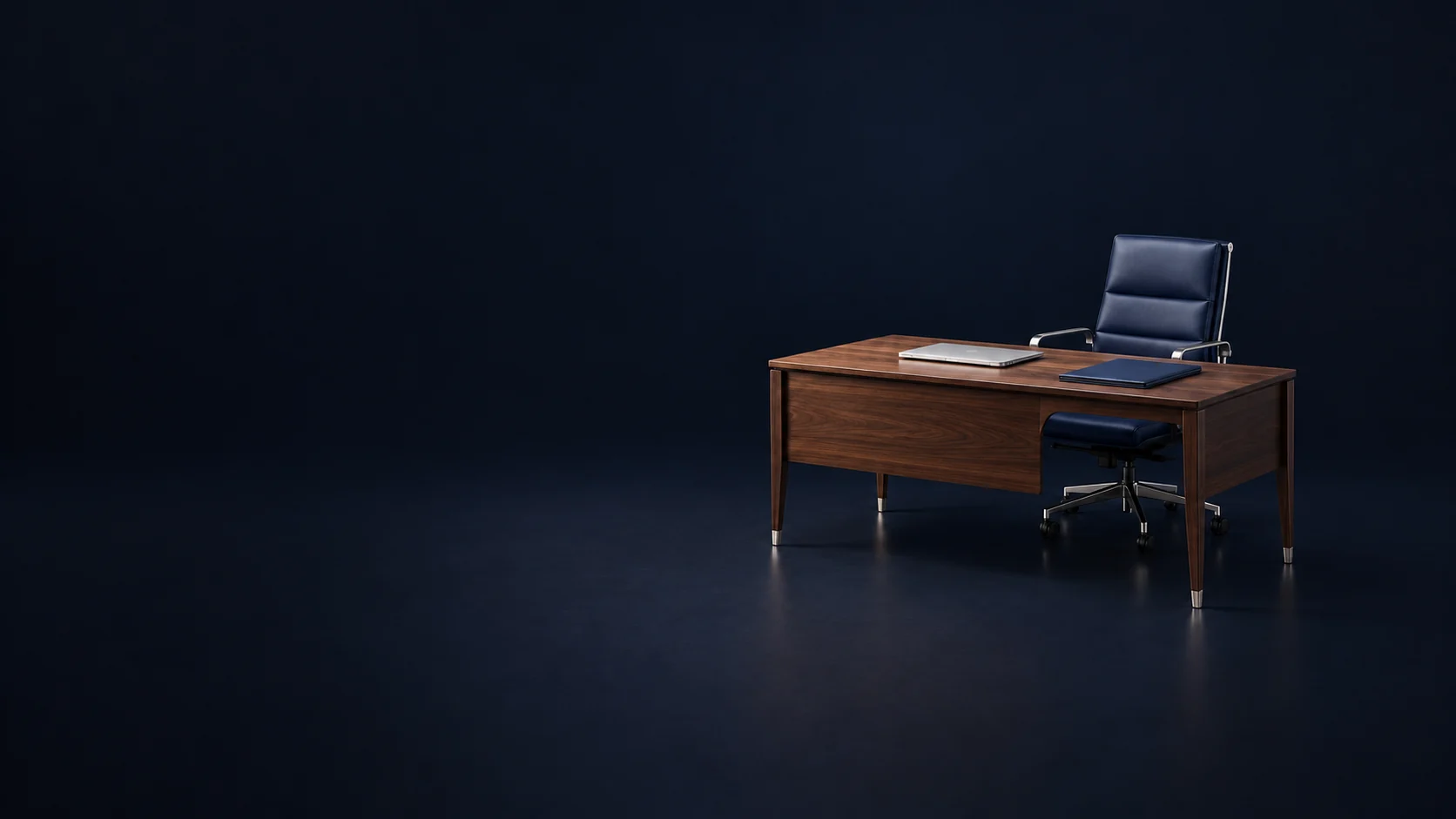 A compact walnut executive desk with a navy chair, closed silver laptop and planning folio.