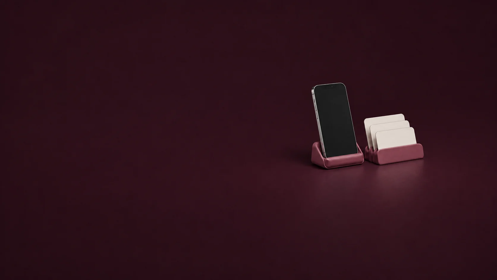 An inactive phone and three blank cards in raspberry desk holders.