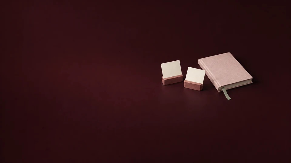 Two blank cards in rosewood holders beside a petal journal and sage bookmark.
