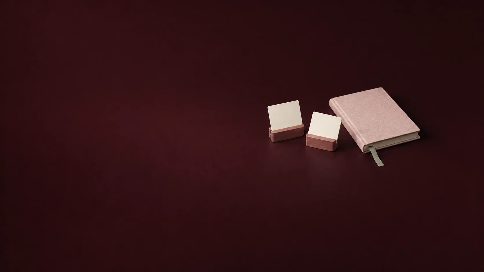 Two blank cards in rosewood holders beside a petal journal and sage bookmark.