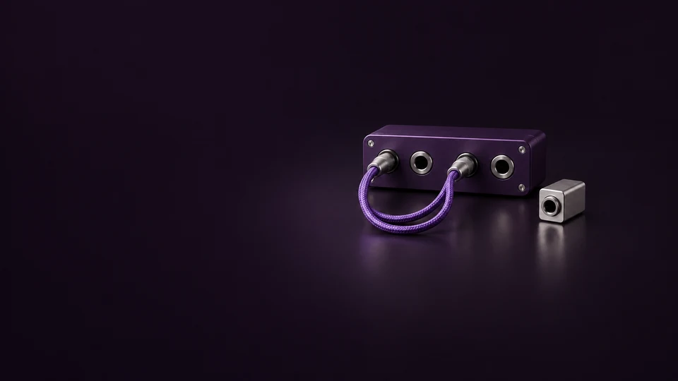 A purple desktop patch panel with a braided cable loop beside a silver adapter.