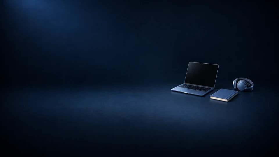 An open laptop with a dark screen beside a blue notebook and folded blue headphones.