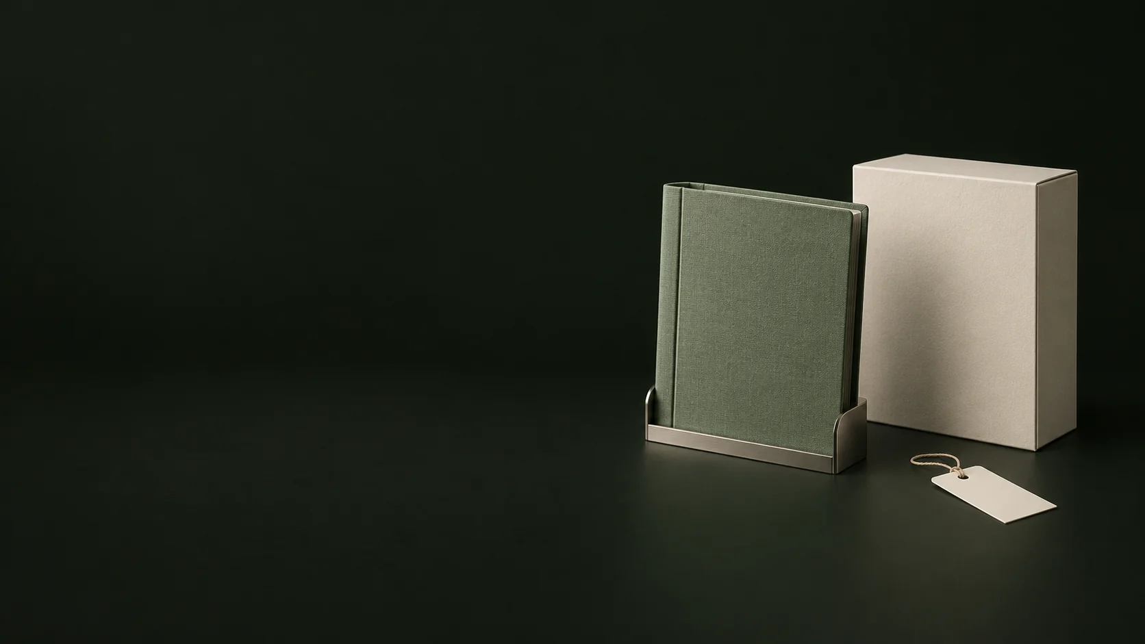 A green document binder in a nickel cradle beside a plain ivory box and blank tag.