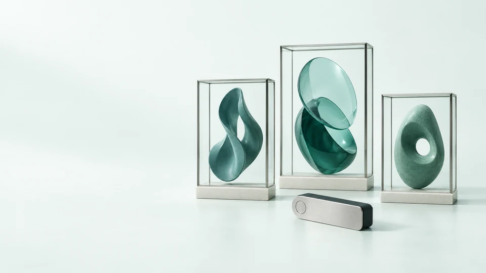 Three original abstract artworks in clear display frames beside an unmarked wallet device.
