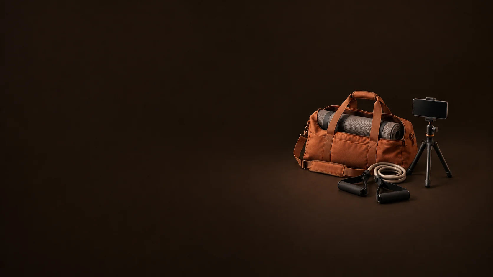 Terracotta training duffel with a rolled mat, resistance handles and an inactive phone on a small tripod.