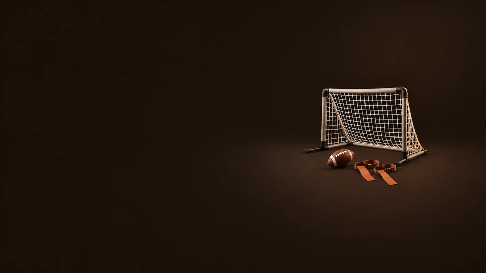 A portable practice goal, a brown football and two terracotta flag belts on a dark brown background.