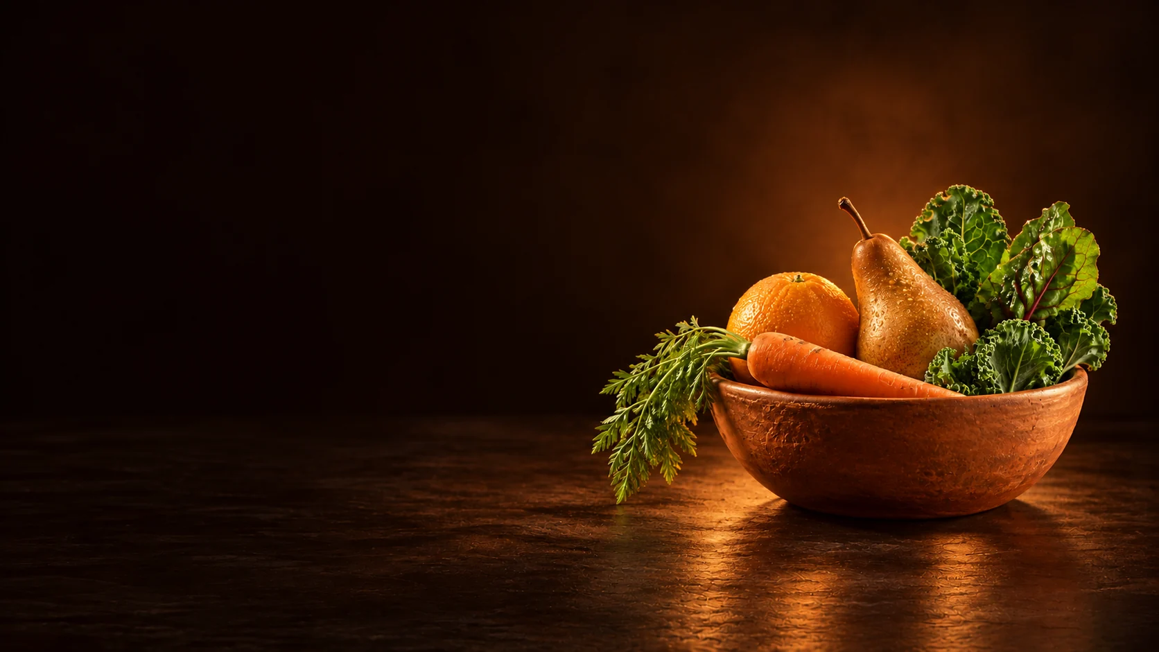 Terracotta bowl holding an orange, pear, carrot and leafy greens.