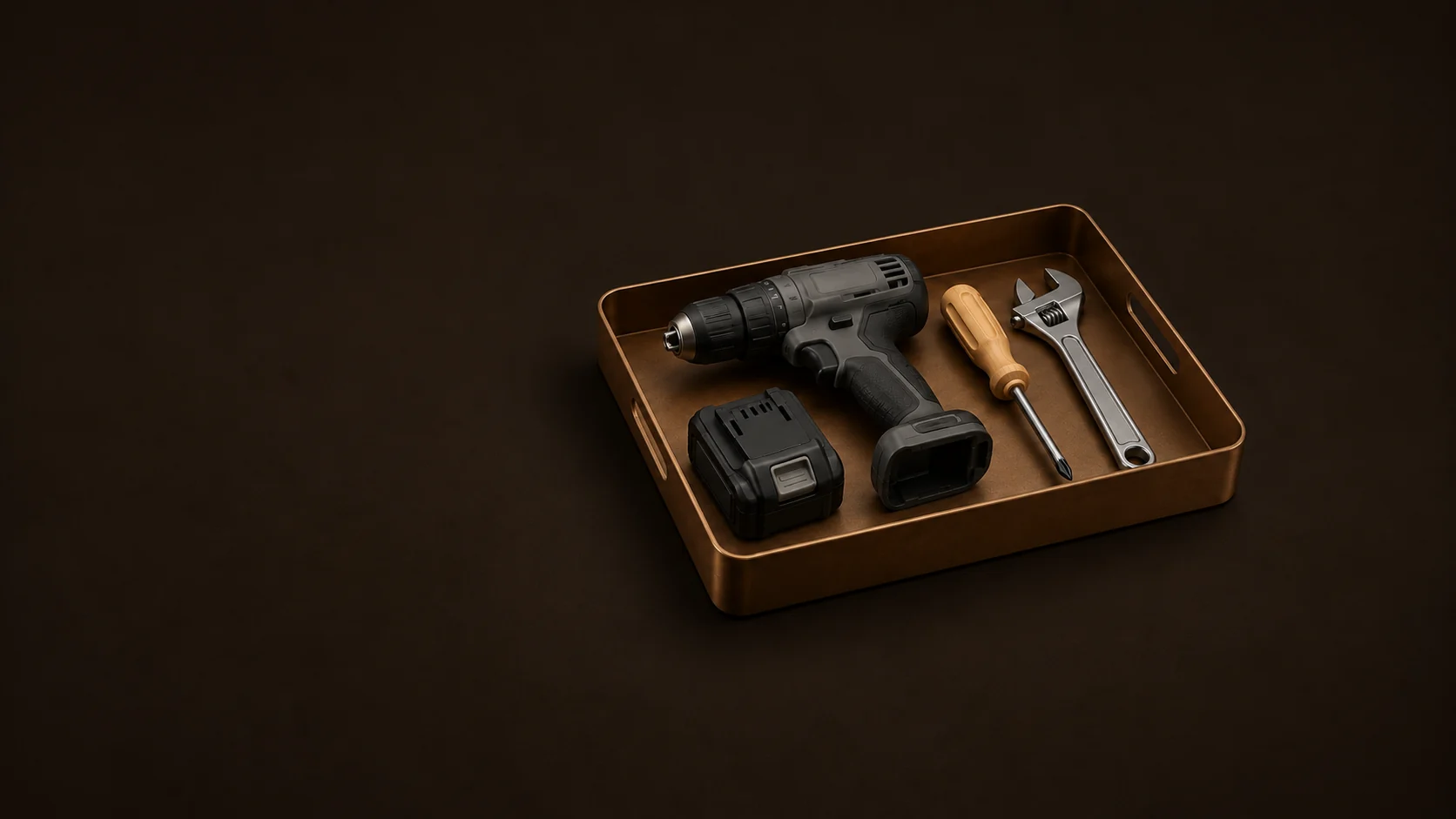 An inactive cordless drill, detached battery, screwdriver and wrench in a low tool tray.
