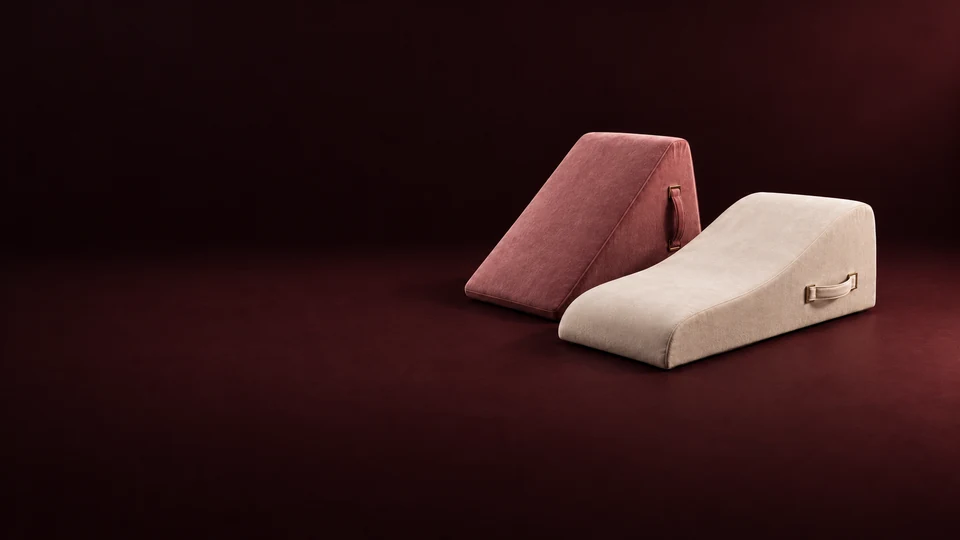 A short rose wedge and a longer ivory upholstered ramp, both with complete fabric handles.