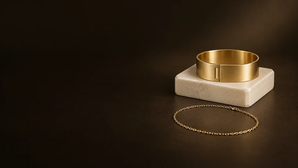 A broad gold-colored cuff on ivory stone with a fine chain loop resting in front.