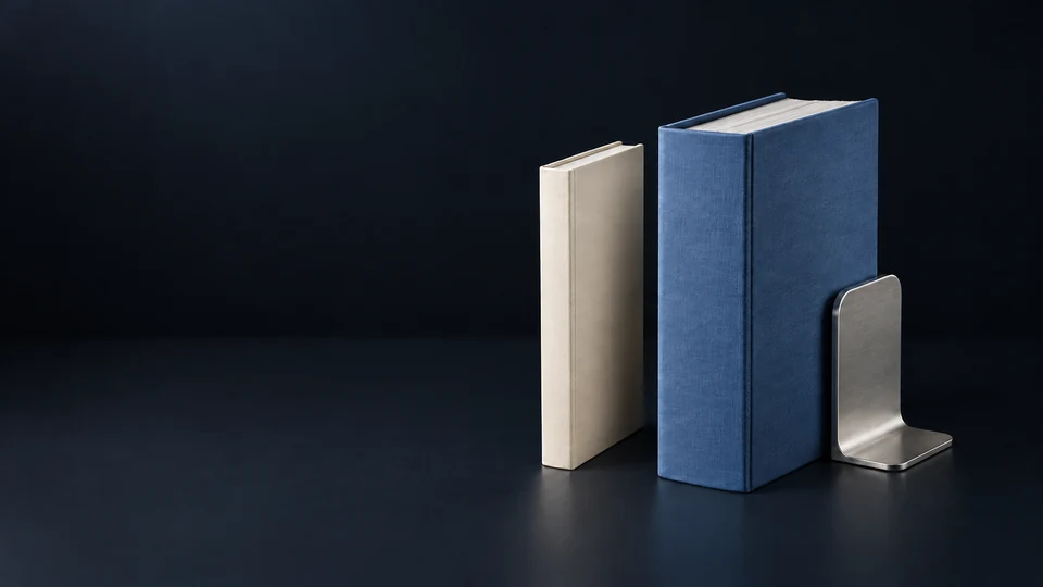 A slim ivory consultation folio beside a deep blue litigation binder and silver bookend.