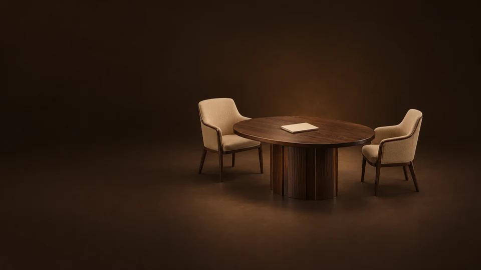 Oval oak meeting table with two empty camel chairs and a plain engagement folder.