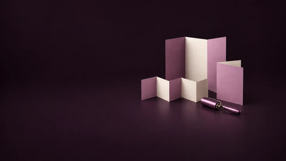 A trifold brochure, accordion fold and half-fold sheet stand beside an orchid inking roller.