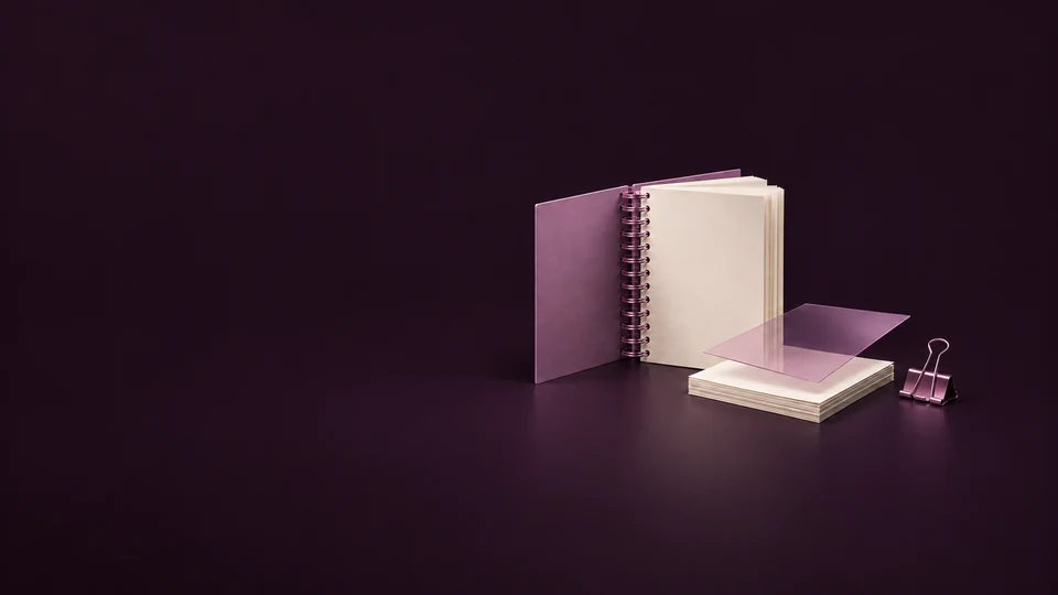 An open orchid spiral manual stands beside a loose paper stack, translucent lamination sheet and binder clip.