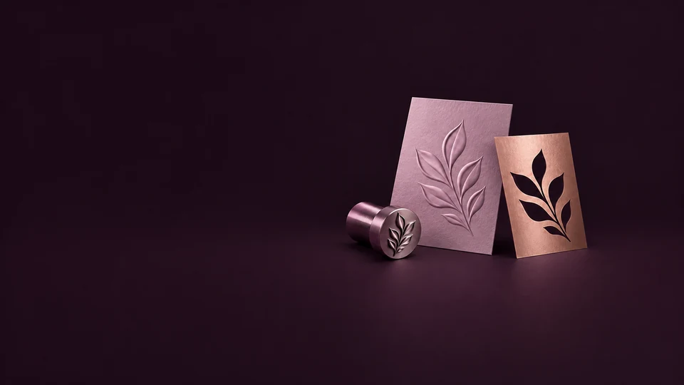 An embossed orchid leaf card stands beside a copper cutout mask and a matching metal embossing die.